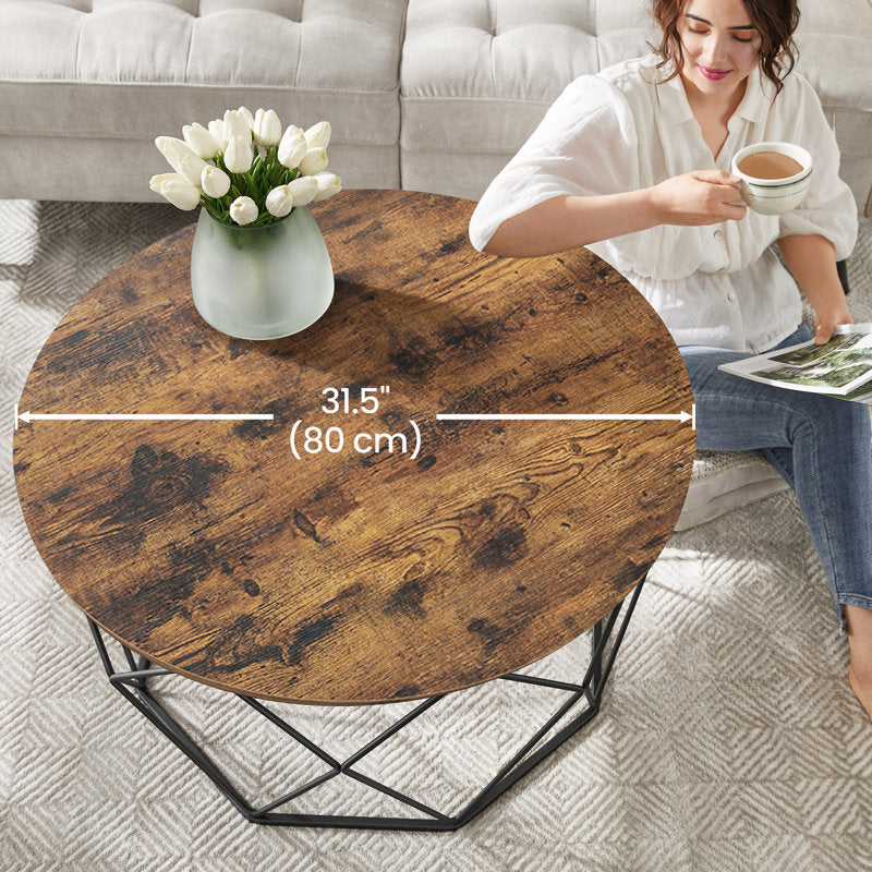 Round rustic brown coffee table with black geometric steel frame in a living room
